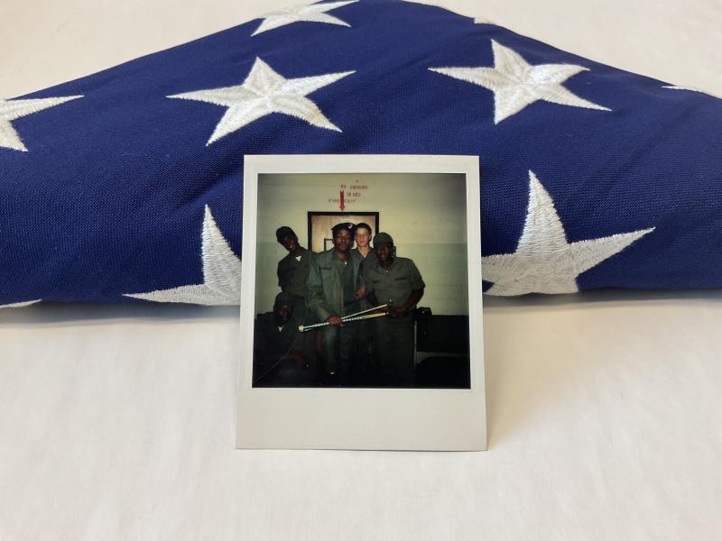 Staged photo of Aubrey E. Weeks, Jr. (Umi’s younger brother) during basic training propped up against the flag given to family at his burial in 2006.